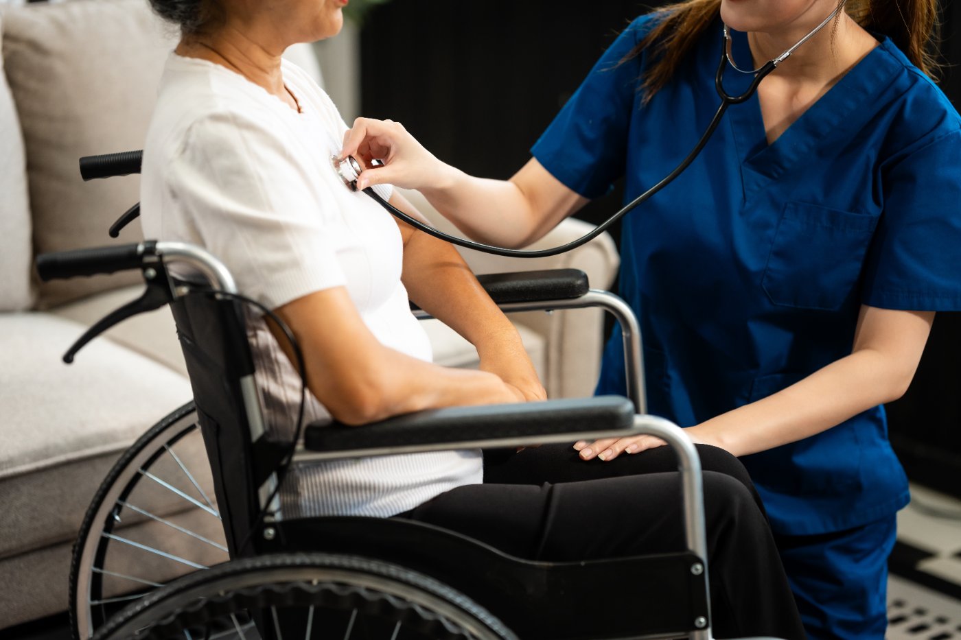 Nurse checking an older patient who uses a wheelchair